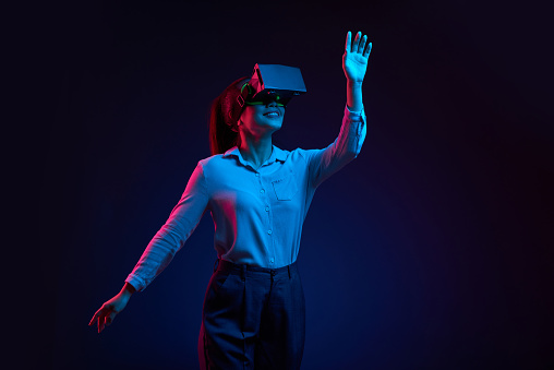 Happy young Asian woman dancing in the dark in virtual reality goggles