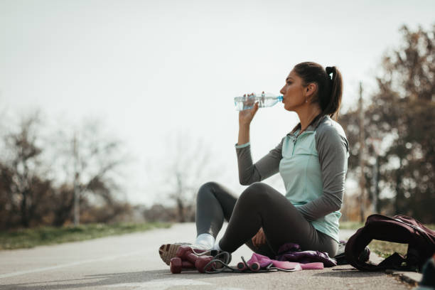 istock Young female athlete relaxing after the training and drinking water 1127908750