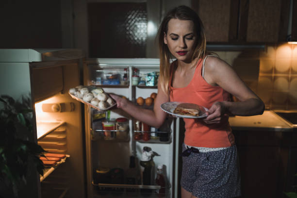 istock Woman eating late night in front of the refrigerator 1127911050