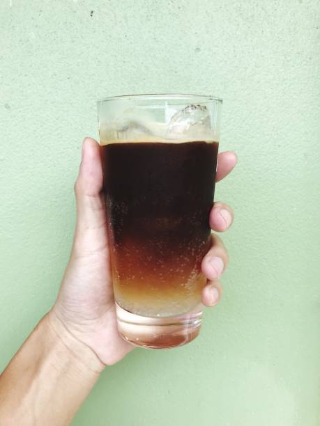 istock Cropped Hand Holding Drink Against Wall 1127911496