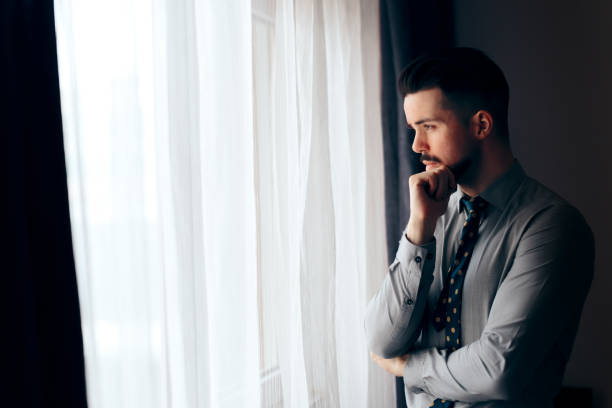 istock Man Looking out the Window Thinking of the Future 1127912688