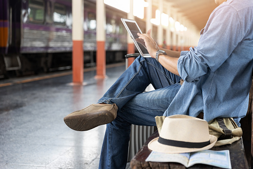 Asian traveler man use tablet to buy train ticket online at train station