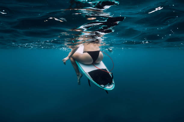 istock Surfer girl sit at surfboard underwater in blue ocean 1127914809