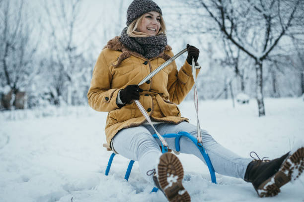 istock Smiling young woman sledding and having fun on a beautiful winter day 1127915165