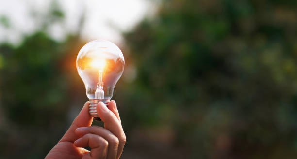 istock hand holding light bulb in nature background. concept solar energy 1127917638