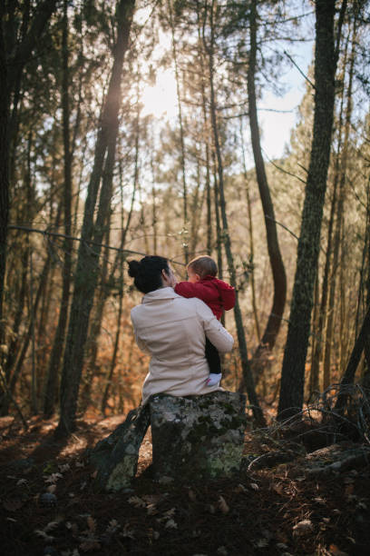istock Rear View Of Mother Carrying Daughter While Standing Amidst Trees At Forest 1127918112