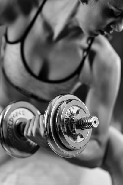 istock Woman Lifting Dumbbell In Gym 1127918115