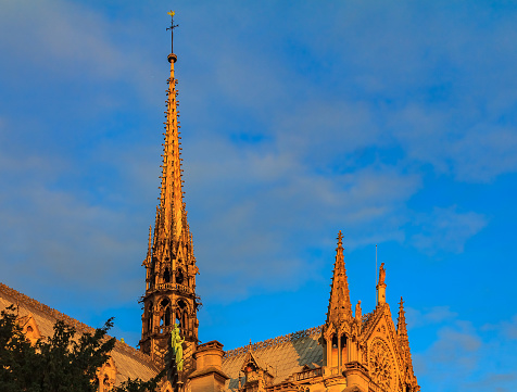 Details of the ornate gothic spire viewed from the southern side of Notre Dame de Paris Cathedral colored by the warm light of sunset