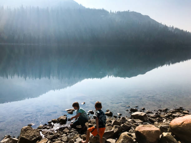 istock Children play by a lake with a beautiful reflection in the mountains 1127923363