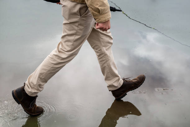 istock Man Holding Umbrella Walking On Wet Asphalt 1127928042