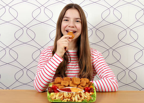 hungry teenage girl eats chicken nuggets stock photo