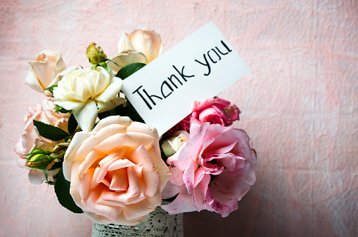 Rose flowers bouquet in a vase with a thank you note