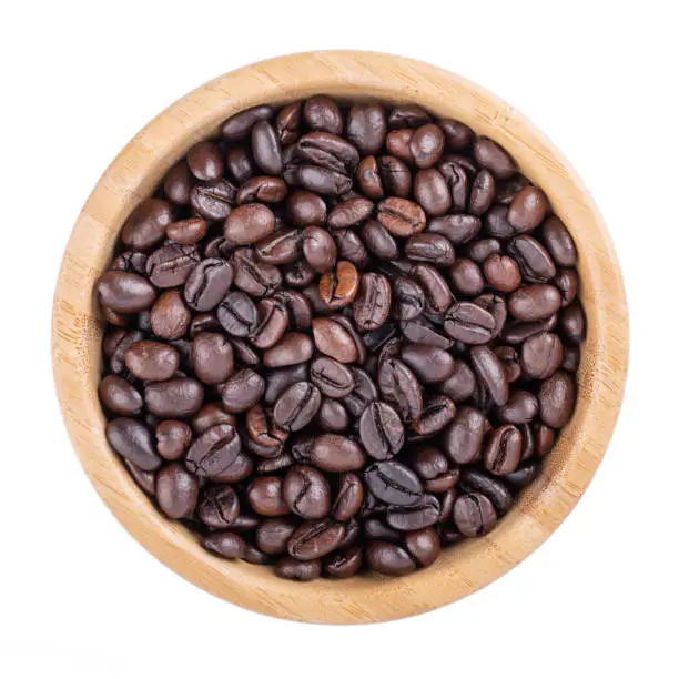 Photo of Coffee beans in wooden bowl isolated on white. Elephant dung coffee. Top view.