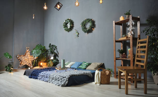 istock Beautiful Loft decor in a studio against a gray wall. Low bed with plaids, wooden shelving, chair, garlands 1127932943