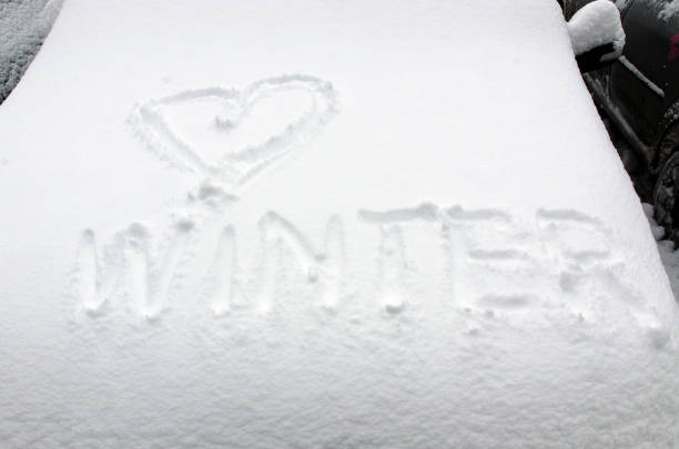 Love Winter words written on a car covered in snow in front of suburban townhouses after a big winter snowstorm.