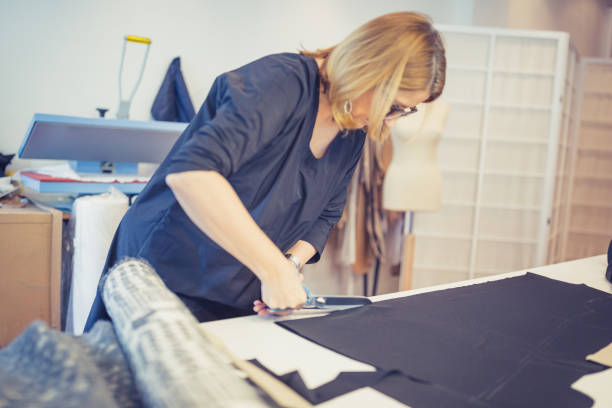 istock Fashion designer, cutting textile with scissors 1127939862