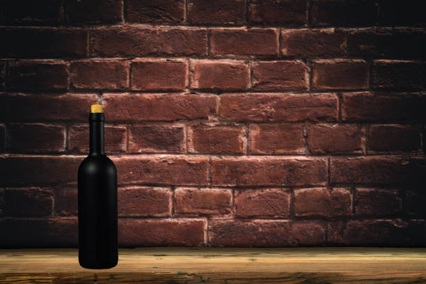 istock Black wine bottle on a old oak table  and background wall. 1127940516
