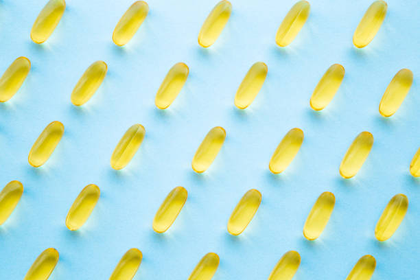 fish oil capsules on light pastel blue table. yellow, transparent nutritional supplements pattern. medical, pharmacy and healthcare concept. closeup. - perscription capsule frame pill imagens e fotografias de stock