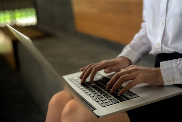 istock Woman hands typing laptop computer keyboard on her lap at the office with sun flare effect- woman office worker and businesswoman concept 1127942042