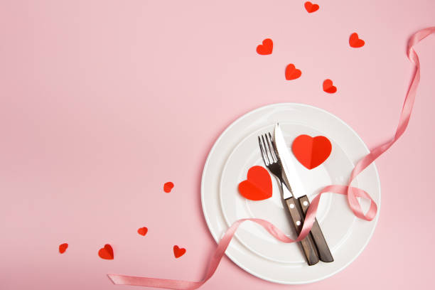 istock Festive table setting for Valentine's Day with fork, knife,  hearts on a red background. Top view. - Image 1127942753