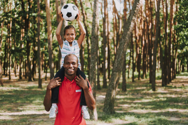 istock Daughter Sits On Fathers Shoulders With Ball. 1127942926
