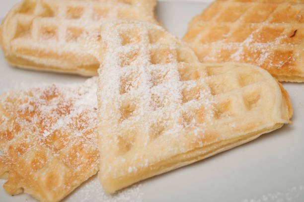 waffle in shaped heart with sugar in a white plate
