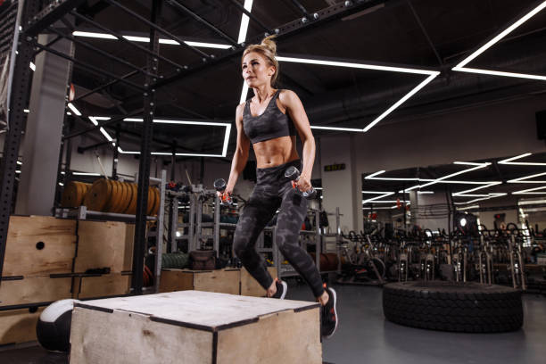 istock blond active sportswoman is jumping over the box in a cross-training gym 1127949865