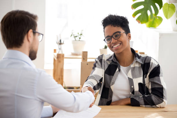 happy confident african applicant shaking hand of hr getting hired - resume interview recruitment human resources imagens e fotografias de stock