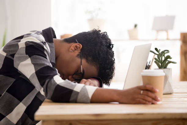 aburrido agotada mujer afroamericana caer dormido para dormir en el lugar de trabajo - perder el tiempo fotografías e imágenes de stock