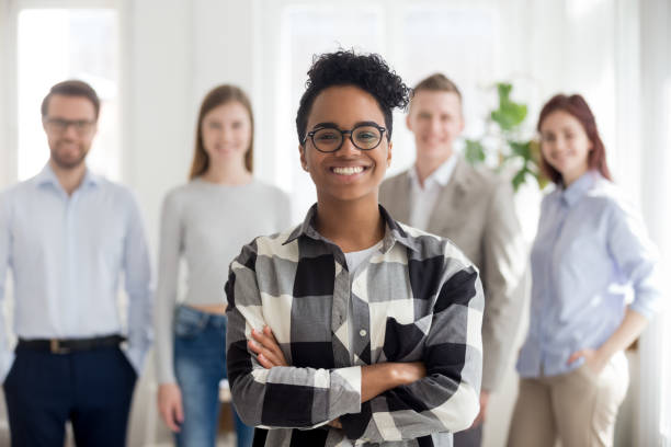 istock Smiling confident black company employee standing with colleagues at background 1127950053