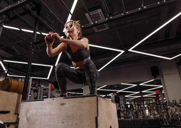 fit young ambitious woman doing a box jump exercise. fit young ambitious blond woman doing a box jump exercise.hobby. side view full length photo. people concept blonde female bodybuilders stock pictures, royalty-free photos & images