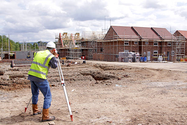 A Senior construction male engineer working with the theodolite camera at the housing  under construction