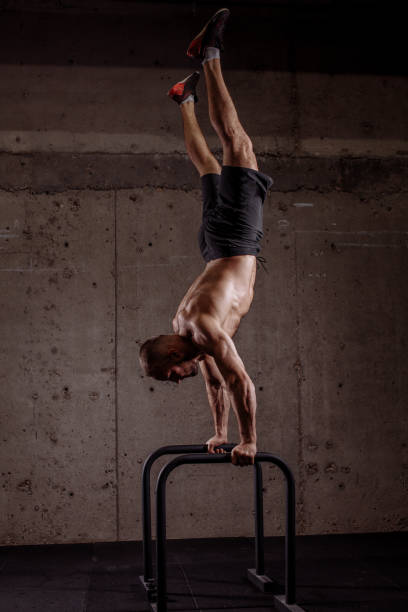 istock young ambitious sporty man performing hand stand on P bars 1127955829