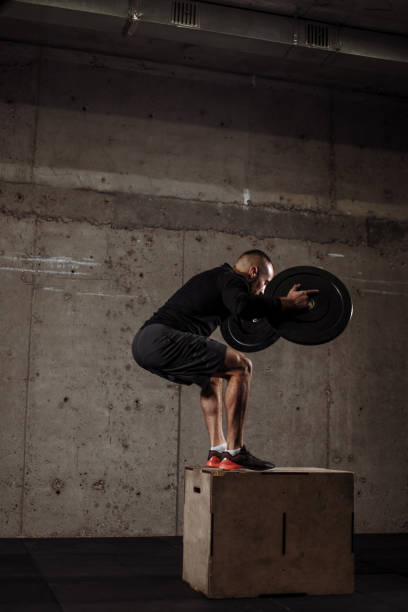 istock strong fit man is doing ups and downs with weight plates 1127956661