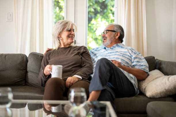 istock Senior couple sitting on the sofa and drinking tea and laughing 1127957429