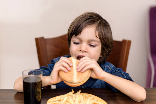 istock little boy indoors eating a  burger 1127958542