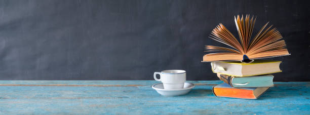 istock open book on a stack of books and a cup of coffee. Reading, learning, education, literature, panorama, good copy space 1127963632