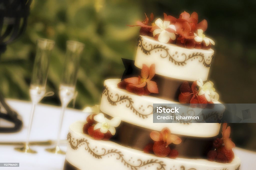 Taças de champanhe e bolo de casamento decorado com flores vermelhas - Foto de stock de Amor royalty-free