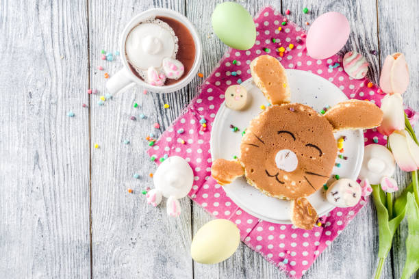 Funny easter kids pancake Funny easter breakfast food, kids pancake in form of bunny rabbit, with hot chocolate, top view wooden background copy space bunny pancake stock pictures, royalty-free photos & images