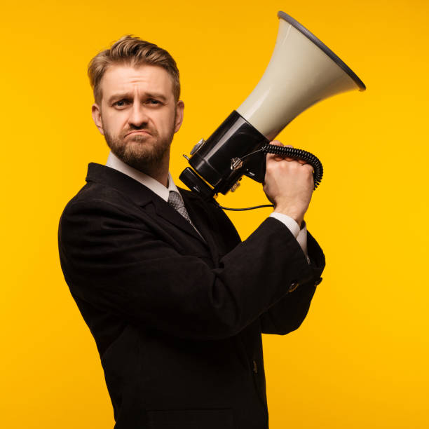 istock Business man with a megaphone on yellow background 1127970220