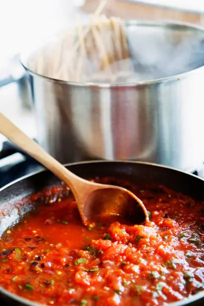 Vilnius, Lithuania - June 17, 2011: preparing of a homemade tomato sauce in a frying pan from fresh tomatoes.