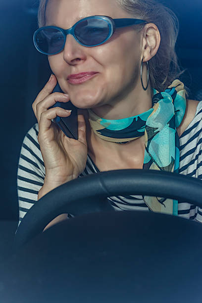 женщина говорить на сотовый телефон во время вождения автомобиля - luxury car women smart phone стоковые фото и изображения