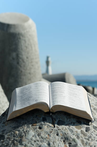istock Open Bible on a big stone on a beautiful day with sky. Vertical image with space for text. Close-up. 1127974882