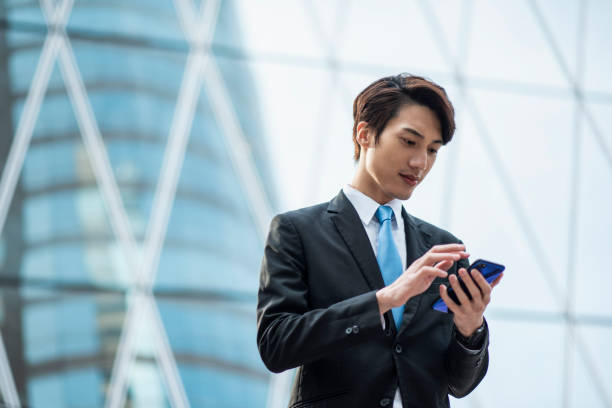 istock Chinese businessman using a smart phone in front of an office building 1127975146