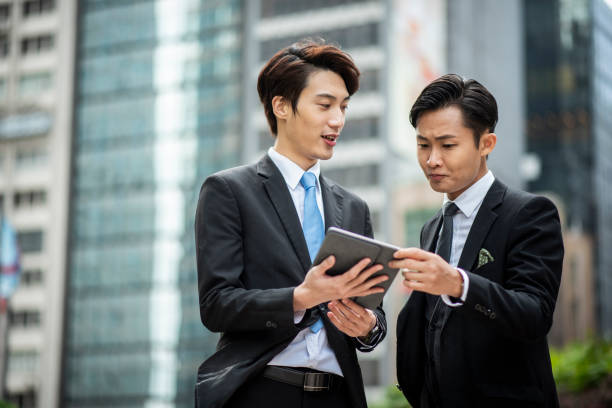 istock Two businesspeople standing outside and talking and using digital tablet 1127975161