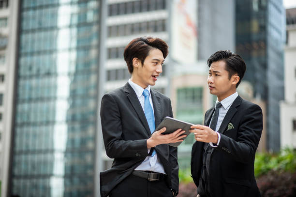 istock Two businesspeople standing outside and talking and using digital tablet 1127975164