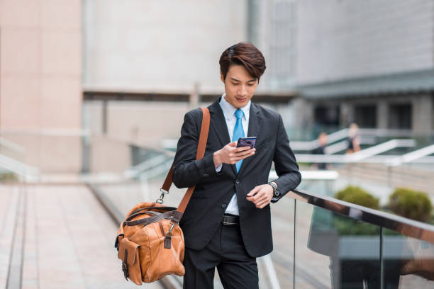 istock Chinese businessman using a smart phone outdoors in the city 1127975170
