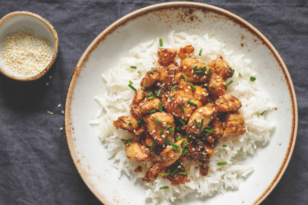 istock Top view on sesame chicken pieces with rice on a ceramic plate. Chinese traditional dish. Copy space. 1127975522