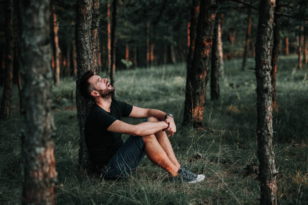 istock Young depressed man sitting alone in the forest 1127975729