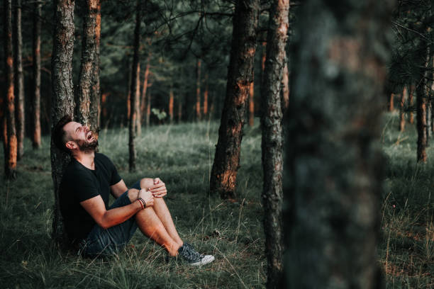 istock Young depressed man sitting alone in the forest 1127975730